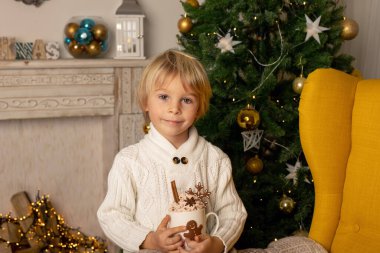 Tatlı çocuk, oğlum, Noel için süslü bir odada sarı bir koltukta oturuyor, rahat bir yer.