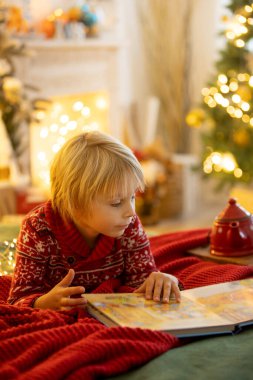 Tatlı çocuk, oğlum, Noel için süslü bir odada sarı bir koltukta oturuyor, rahat bir yer.