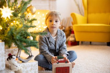 Sevimli anaokulu çocuğu, evcil köpeği olan sarışın çocuk, evdeki süslü Noel odasında oynuyor.