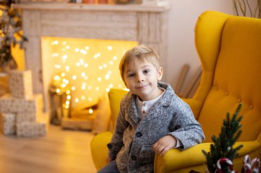 Sevimli anaokulu çocuğu, evcil köpeği olan sarışın çocuk, evdeki süslü Noel odasında oynuyor.