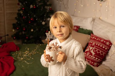 Tatlı çocuk, oğlum, Noel için süslü bir odada sarı bir koltukta oturuyor, rahat bir yer.