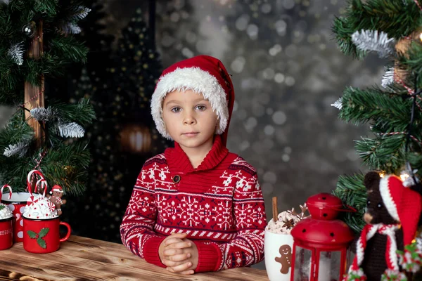 可爱的小孩 金发男孩 站在雪地上的木制看台上 装饰着圣诞节 喝着热巧克力 吃着饼干 — 图库照片