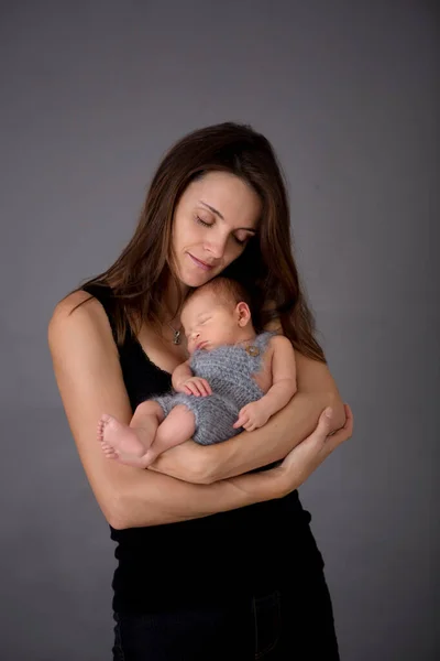 母亲在灰暗的背景下亲吻和拥抱新生的儿子 女人和小宝宝的画像 幸福的概念 孤独的形象 — 图库照片