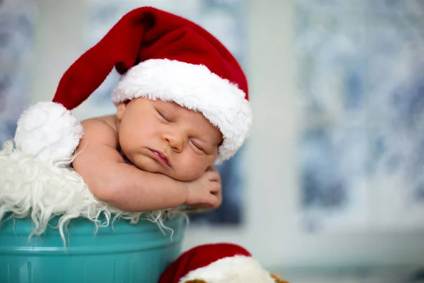 初生男婴 戴着圣诞帽 睡在一个蓝色的桶 圣诞装饰灯笼在他周围 靠窗户 外面的雪的肖像 — 图库照片