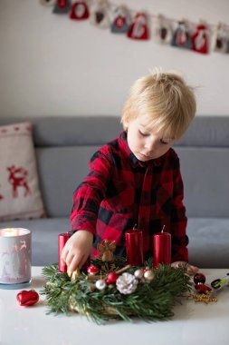 Küçük tatlı sarışın çocuk, evde çelenk yapıyor, dekore ediyor.