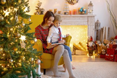 Anne ve çocuk, sevimli sarışın çocuk, rahat koltuğunda oturuyor, birlikte kaliteli aile zamanlarının tadını çıkarıyor.