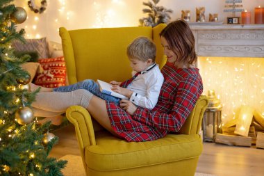 Anne ve çocuk, sevimli sarışın çocuk, rahat koltuğunda oturuyor, birlikte kaliteli aile zamanlarının tadını çıkarıyor.