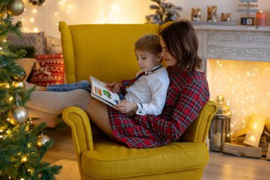 Anne ve çocuk, sevimli sarışın çocuk, rahat koltuğunda oturuyor, birlikte kaliteli aile zamanlarının tadını çıkarıyor.