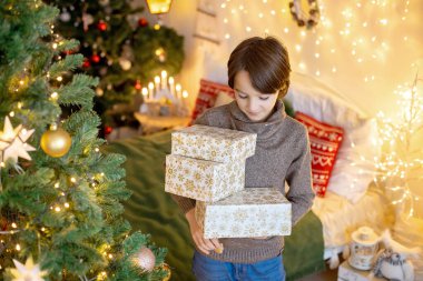 Tatlı çocuk, oğlum, Noel için dekore edilmiş odada oynuyor, Noel ağacını süslüyor.