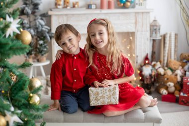 Mutlu şirin çocuklar, Noel 'de kardeşler, tatilin tadını çıkarın, hediyeleri açın ve kurabiye yiyin.