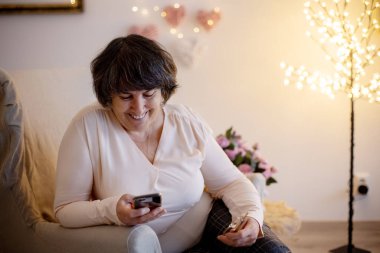 Yaşlı kadın, evde poz veriyor, kanepede ya da yatakta oturuyor.