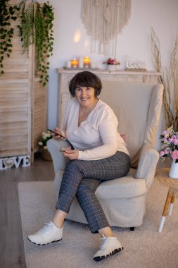 Yaşlı kadın, evde poz veriyor, kanepede ya da yatakta oturuyor.