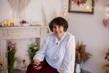 Yaşlı kadın, evde poz veriyor, kanepede ya da yatakta oturuyor.