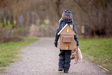 Little child, blond boy with pet dog, carying home on his back, kid, having paper house, emotional shot