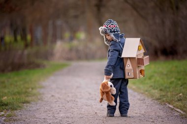 Little child, blond boy with pet dog, carying home on his back, kid, having paper house, emotional shot