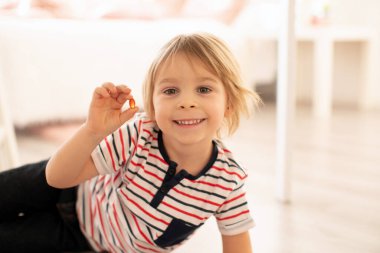 Sevimli küçük çocuk, küçük çocuk, alfa omega 3 çocuk vitamin hapları yiyor evde daha iyi bir dokunulmazlık için.
