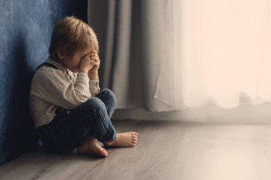 Sevimli sarışın anaokulu çocuğu, evcil köpekle yerde oturuyor, yaramazlık yaptığı için cezalandırılıyor, anneme kızgın.