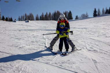 Mutlu bir aile, güneşli bir günde İtalya 'da kayak, çocuklar ve yetişkinler birlikte kayak yapıyor. Aile tatili