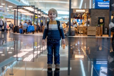 Havalimanı geçiş koridorunda kalkış kapısında bekleyen sevimli bir oğlan çocuğu. Aktif aile hayatı tatilde çocukla hava yoluyla seyahat