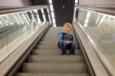 Havalimanı geçiş koridorunda kalkış kapısında bekleyen sevimli bir oğlan çocuğu. Aktif aile hayatı tatilde çocukla hava yoluyla seyahat