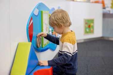 Havalimanı geçiş koridorunda kalkış kapısında bekleyen sevimli bir oğlan çocuğu. Aktif aile hayatı tatilde çocukla hava yoluyla seyahat