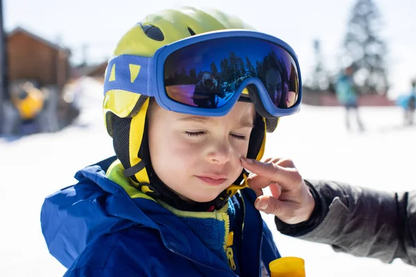 在她的滑雪孩子身上涂防晒霜 家人在滑雪寒假 对高山上的烈日采取措施 — 图库照片