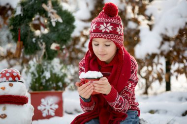 Tatlı okul çocuğu, çocuk, bahçede karla oynuyor, kardan adam yapıyor, kışın dışarıda mutlu bir çocuk.