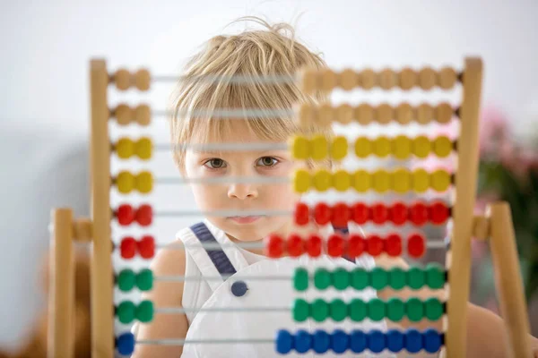 可爱的幼儿 金发碧眼的男孩 在家里用五颜六色的算盘学习数学 喝新鲜的果汁 — 图库照片