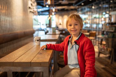 Child, visiting little town in south Norway, Arendal, on a rainy summer day, sitting in a coffee shop