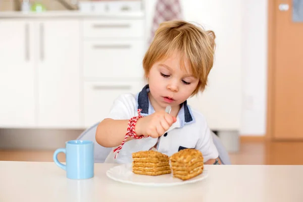 かわいい就学前の男の子 金髪の子供 ケーキを食べ 家で牛乳を飲む 幸せな笑顔 — ストック写真