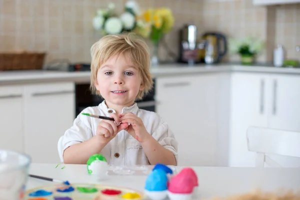 美しいブロンドの子供 幼児の男の子 自宅で母親とイースターの卵を描く 虹色でイースターの花輪を作る — ストック写真