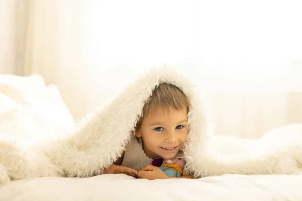 小さな幼児の子供 かわいいです子供とともにニット小さなかわいい動物のおもちゃ ベッドに横たわっています 抱っこ — ストック写真