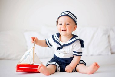 Şirin bebek çocuk, giyinmiş ahşap tekne ile oynarken deniz giysili