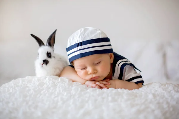 かわいい男の子服を着た海洋 木製ボートとかわいい赤ちゃんウサギの寝室で眠っています — ストック写真
