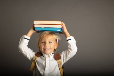 Cute preschool blond child, boy, holding books and notebook, apple, wearing glasses, ready to go to school