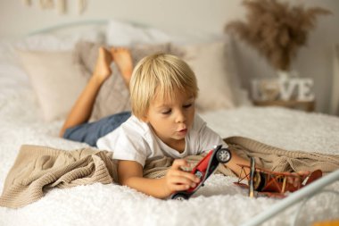 Tatlı anaokulu çocuğu, arka planda uçak, balon ve doğum günü süslemeleriyle oynuyor.