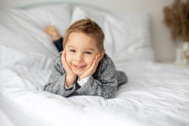 Şirin bir çocuk, beyaz gömlekli bir çocuk, Paskalya süslemesinde yumurta ve çikolatalı tavşanla oynuyor, stüdyo fotoğrafı.