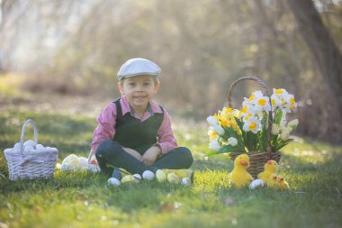 Güzel, şık bir çocuk, evlat, parkta paskalya süslemeleriyle oynuyor, bahar zamanı.
