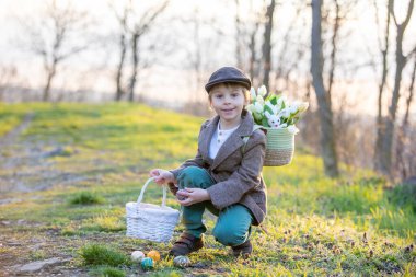 Güzel, şık bir çocuk, evlat, parkta Paskalya süslemeleriyle oynuyor, gün batımında ilkbahar.