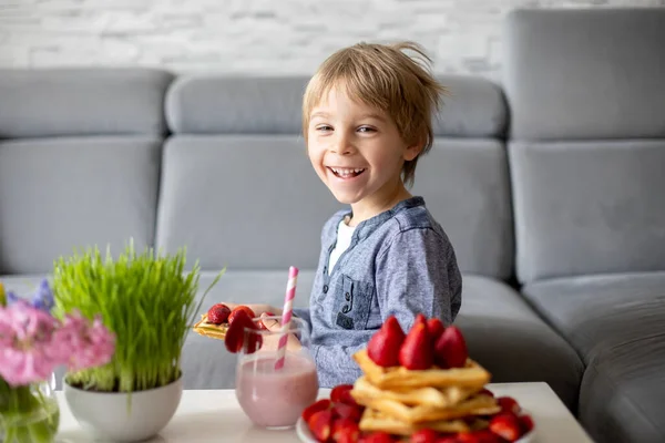 甜美的学龄前儿童 在家里吃着带有草莓和巧克力的比利时华夫饼和滴滴的冰沙 — 图库照片