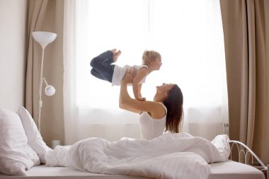 Güzel sarışın çocuk ve annesi, sabahları evde oynuyorlar, gülüyorlar, gülüyorlar ve birlikte eğleniyorlar.