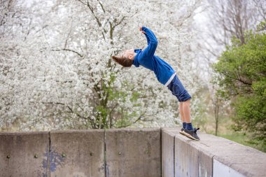 Genç çocuk, çocuk, baharda parkta takla atıyor.