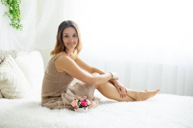 Orta yaşlı bir kadın, evde doğum gününü kutluyor, yatakta oturuyor.