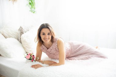 Orta yaşlı bir kadın, evde doğum gününü kutluyor, yatakta oturuyor.