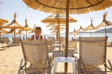 Child, cute boy, playing on the beach in the sand, enjoying summer, number sign