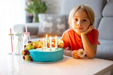 Doğum günü pastası ve mumları olan sevimli anaokulu çocuğu arkadaşlarıyla ve kardeşleriyle partiye hazırlanıyor.