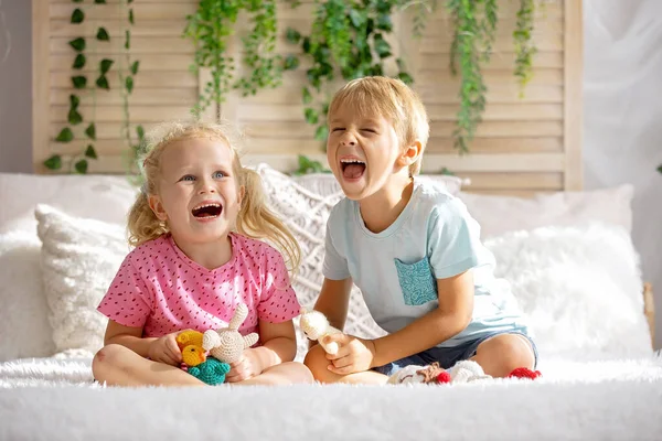 Cute sweet toddler children, tickling feet on the bed, laughing and smiling, childish mischief, happiness and joy