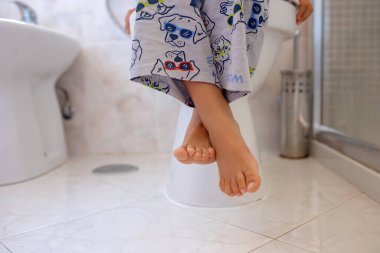 Sevimli çocuk, banyoda tuvalette oturuyor.