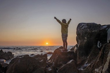 Mutlu çocuklar, Portekiz 'de kayalık plajda aileleriyle günbatımının tadını çıkarıyorlar.