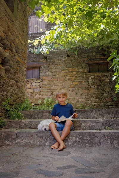 Beautiful medieval village Talasnal in Lousa, Portugal on a beautiful day. Child playing on the street of the village with his pet dog, reading book